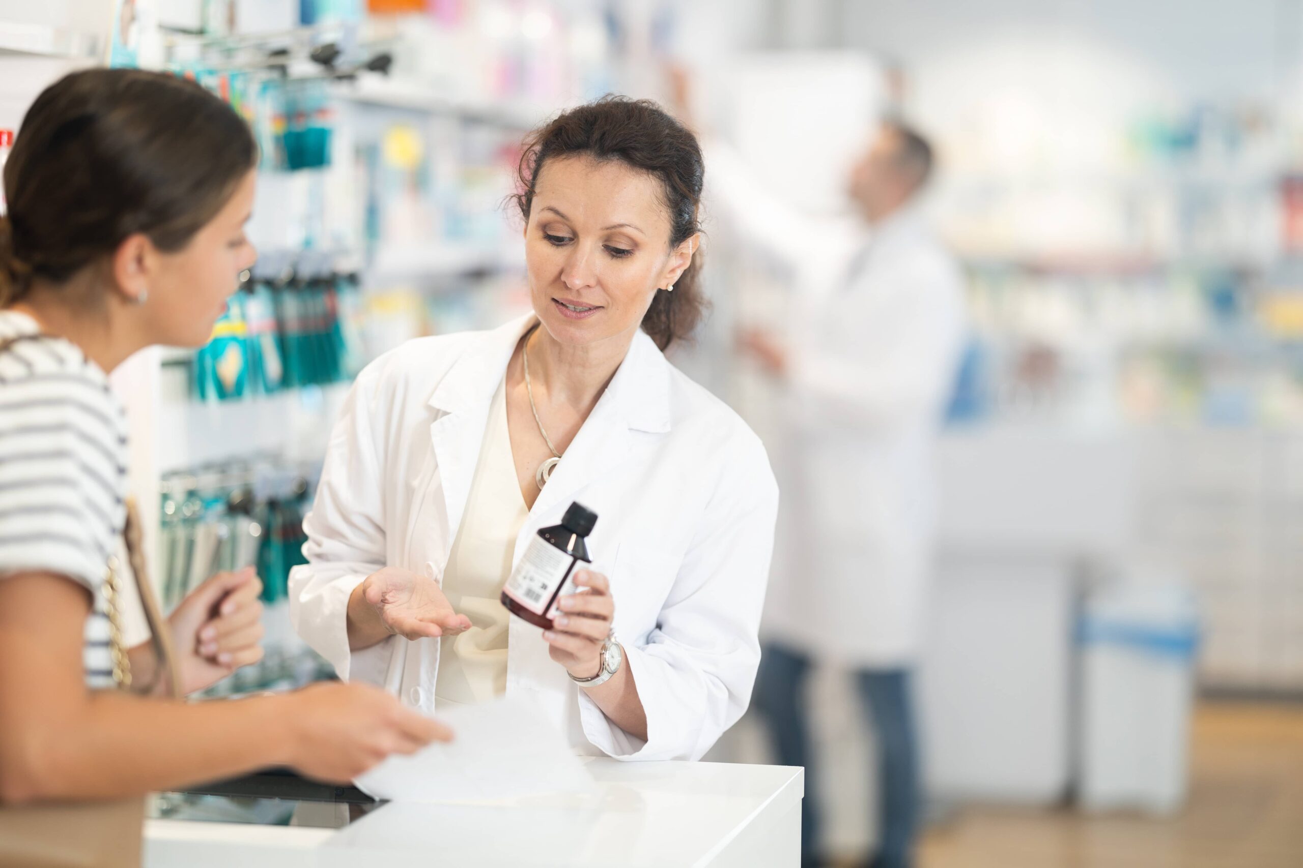 Apotheker erklärt einem Kunden an der Apothekentheke die Medikamenteneinnahme.