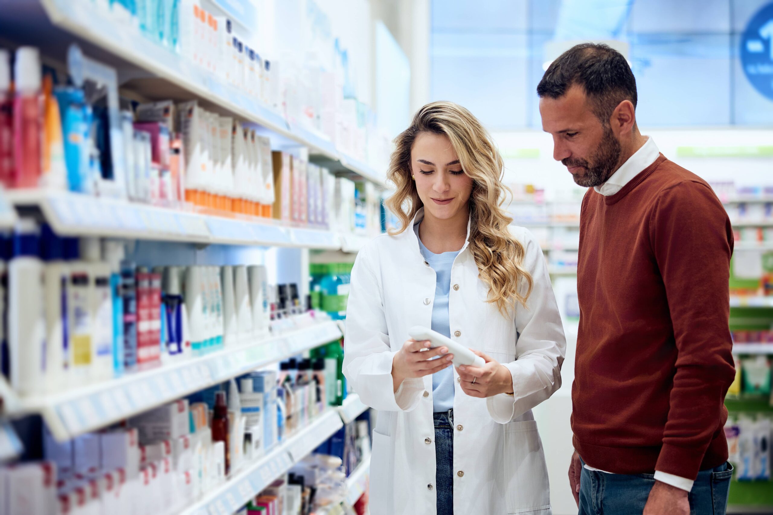 Apotheker hilft Kunden bei der Auswahl von Gesundheitsprodukten im Apothekengang